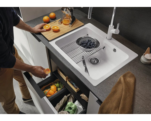 Küchenszene mit Spüle, Mülltrennsystem und Person, die Abfall entsorgt