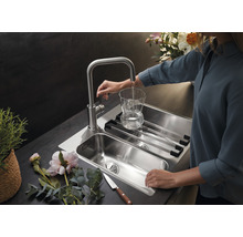Edelstahlspüle mit Abtropfgestell und Wasserhahn, der ein Glas befüllt