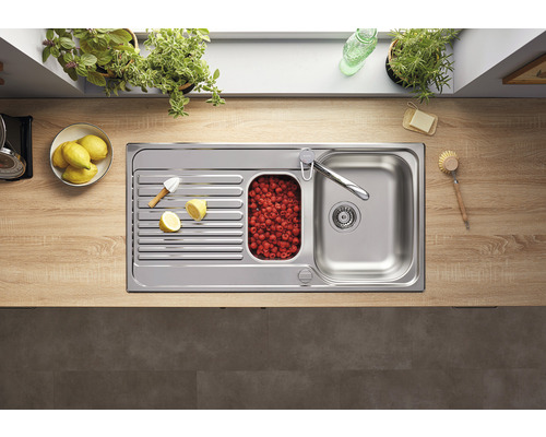 Edelstahlspüle mit Abtropffläche, kleinem Becken mit Himbeeren und Armatur auf einer Küchentheke