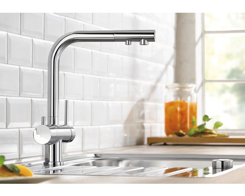 Küchenarmatur aus Chrom im Spülbecken vor Fliesenwand