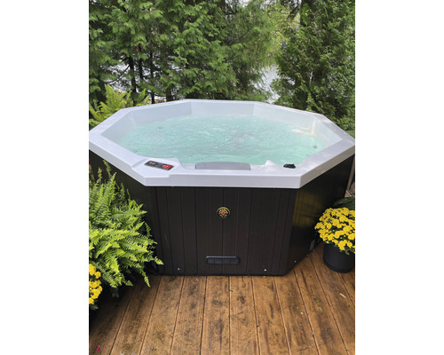 Achteckiger Whirlpool mit Wasser auf einer Holzterrasse