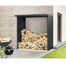 Brennholzlager mit Holz und Schubkarre vor einer Hauswand.