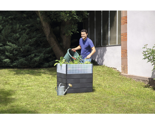 Hochbeet aus Holzimitat mit Mann, der Pflanzen einsetzt, und Gießkanne im Garten