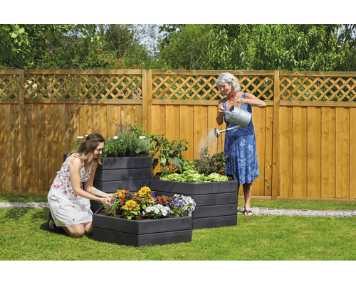 Garten mit Hochbeeten, bepflanzt mit Blumen und Gemüse, zwei Frauen
