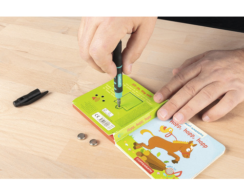 Ein Mann wechselt die Batterien in einem Kinderbuch mit einem Schraubendreher.