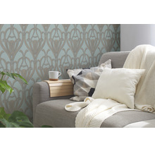 Wohnzimmer mit floral gemusterter Tapete, Couch, Kissen und Decke