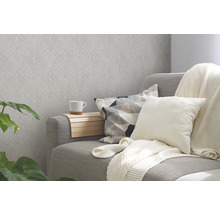 Wohnzimmer mit gemusterter Tapete, Sofa, Kissen und Pflanze für eine gemütliche Atmosphäre