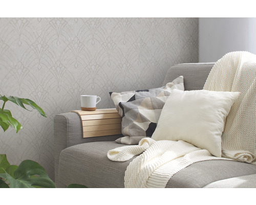 Wohnzimmer mit gemusterter Tapete, Sofa, Kissen und Pflanze für eine gemütliche Atmosphäre