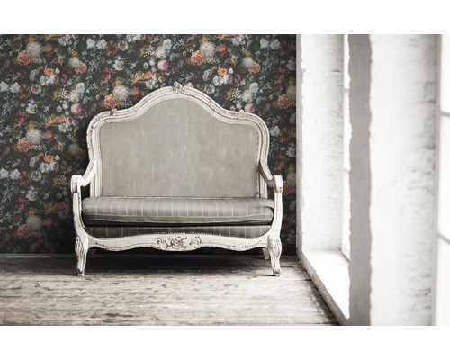 Vintage Sofa vor floraler Tapete in einem hellen Raum.