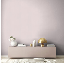 Helles Zimmer mit rosa Wand, Kommode, Tischlampe und Dekorationsartikeln