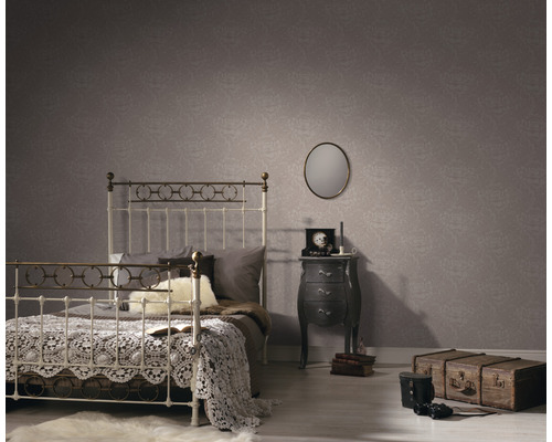 Schlafzimmer mit Bett, Nachttisch und gemusterter Tapete für eine gemütliche Atmosphäre.