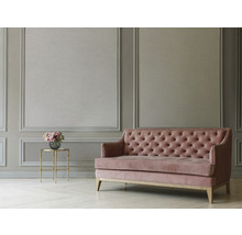 Szene mit einem Sofa mit Knopfheftung und einem Beistelltisch mit Blumenstrauß in einem Raum mit Wandpaneelen