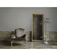 Einrichtung mit Sessel, Spiegel und Kerzenständer in einem Raum.