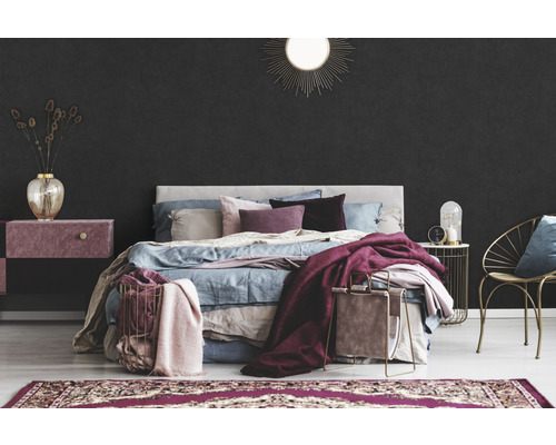Schlafzimmer mit Bett, Nachttisch, Sessel und Teppich