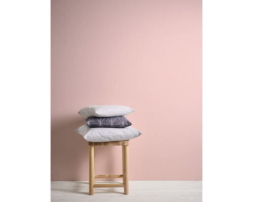 Dekorative Kissen auf einem Hocker vor einer Wand