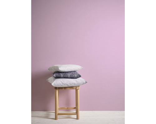 Dekorative Kissen auf einem Hocker vor einer Wand