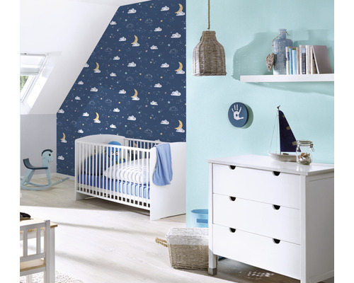 Babyzimmer mit Gitterbett, Kommode und blau gemusterter Tapete
