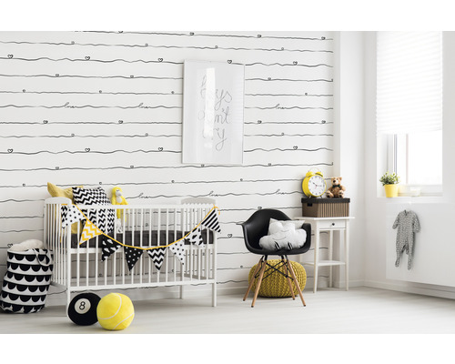 Dekoriertes Kinderzimmer mit Gitterbett, Stuhl und Accessoires vor einer gemusterten Tapete.