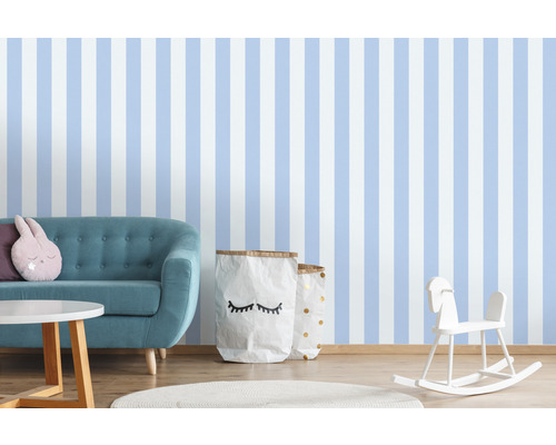 Kindgerechtes Zimmer mit gestreifter Tapete, Sofa, Tisch, Spielzeug und Aufbewahrungssäcken