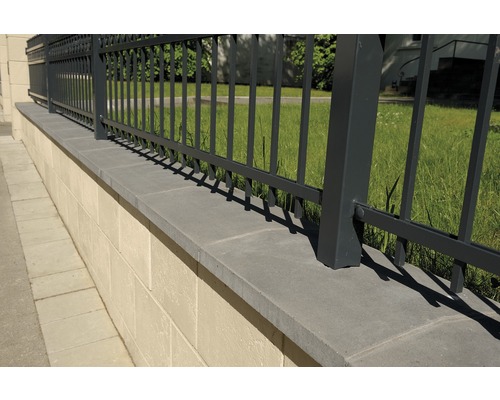 Detailansicht eines Gartenzauns aus Metall auf einer Steinmauer.