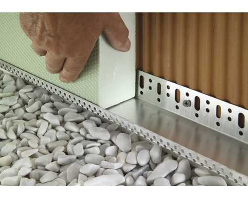 Detailansicht einer Fassadendämmung mit Perimeterdämmplatten und Sockelschienen in einem Kiesbett.