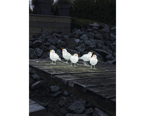 Dekorative Gruppe von sechs weißen Vögeln auf einer Holzoberfläche im Freien