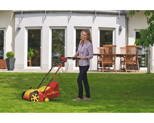 Frau benutzt Rasenmäher von Wolf Garten im Garten.
