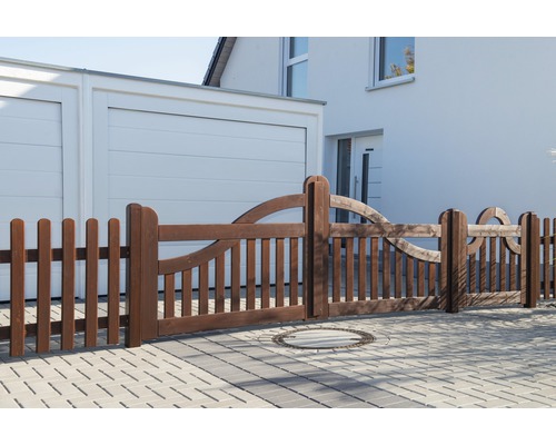 Holzzaun mit dekorativen Elementen vor einem Wohnhaus