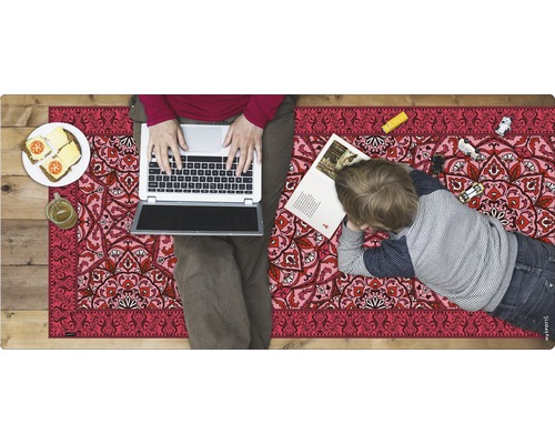 Bodenmatte mit Muster, auf der eine Person mit Laptop sitzt und ein Kind liegt