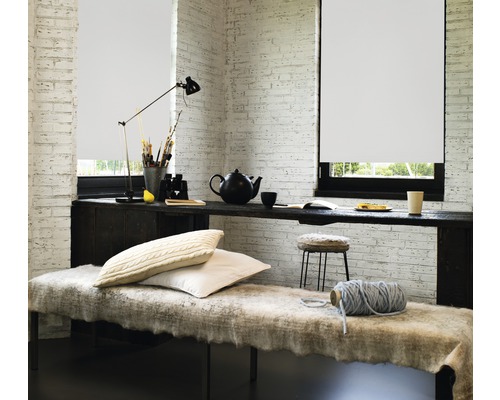 Heller Raum mit Rollo, Schreibtisch und Sitzgelegenheit.