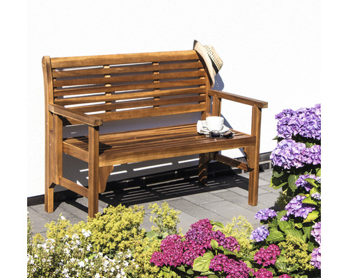 Holzgartenbank mit Armlehnen, Hut, Tasse und Sonnenbrille im Garten