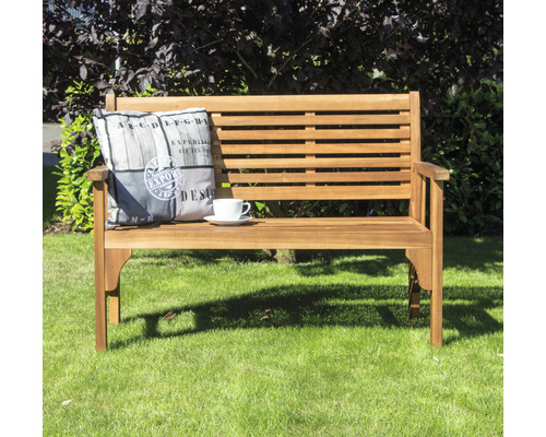 Gartenbank aus Holz mit Kissen und Tasse auf Rasen