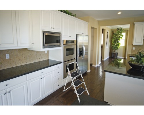 Helle Küche mit weißen Schränken, Edelstahlgeräten und einer Trittleiter