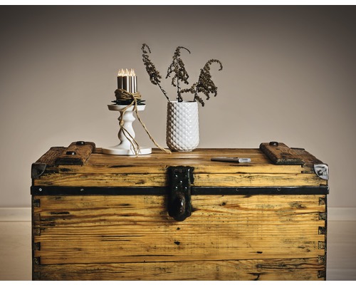 Dekorative Szene mit einer Holzkiste, einer Vase mit Pflanzen und einem Kerzenständer mit Kerzen