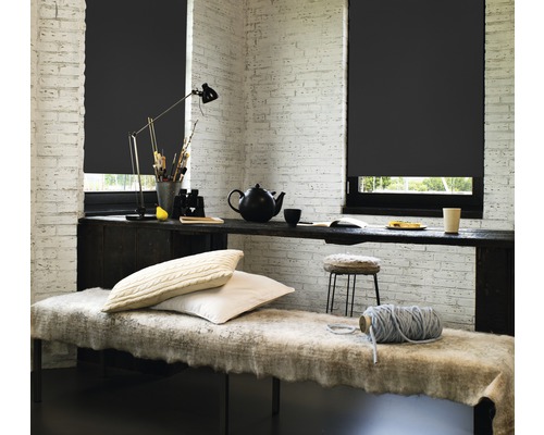 Raum mit schwarzen Rollos, Tisch und Sitzbank vor einer Ziegelwand