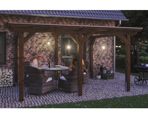 Terrassenüberdachung SKAN HOLZ Siena 434x300 cm nußbaum Holzpergola mit Sitzgruppe auf gepflasterter Terrasse vor einem Backsteinhaus