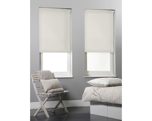 Zwei Fenster mit montierten Rollos in einem Schlafzimmer.