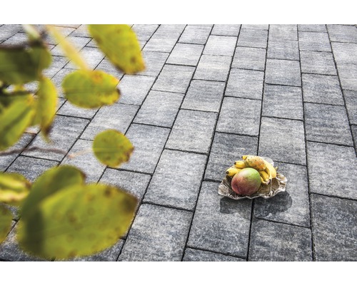 Graue Pflastersteine mit Früchten auf einer Schale im Freien.