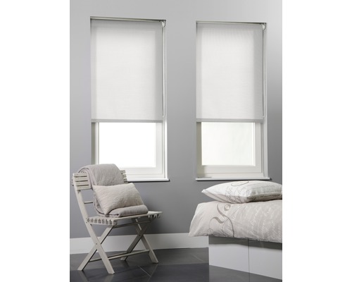 Zwei weiße Rollos an Fenstern in einem Schlafzimmer mit einem Stuhl und einem Bett