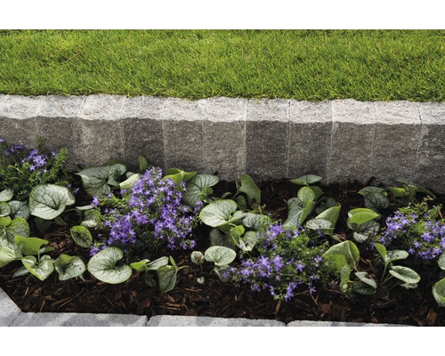 Gartenlandschaft mit Rasen, Steinbegrenzung und Blumenbeet