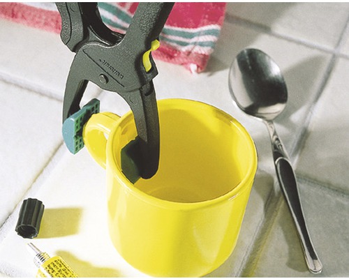 Gelbe Tasse wird mit einer Federklemme fixiert, um einen Klebevorgang zu unterstützen.