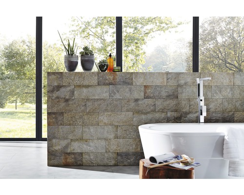 Modernes Badezimmer mit Natursteinwand, freistehender Badewanne und Zimmerpflanzen