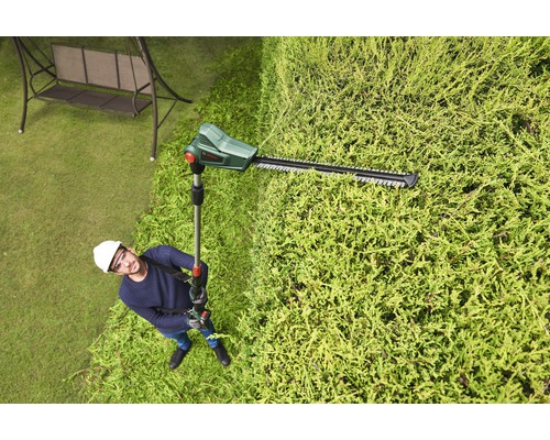 Mann mit einer Akku-Teleskop-Heckenschere bei der Arbeit an einer Hecke
