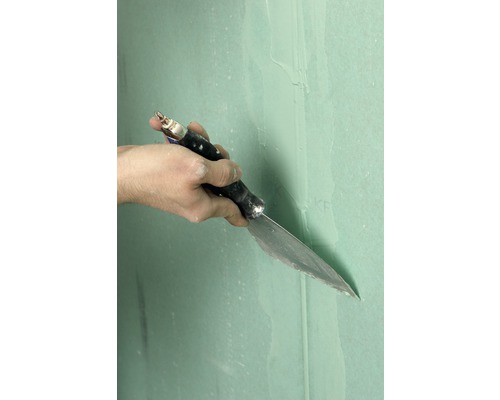 Hand mit Spachtel beim Verspachteln einer Gipskartonwand