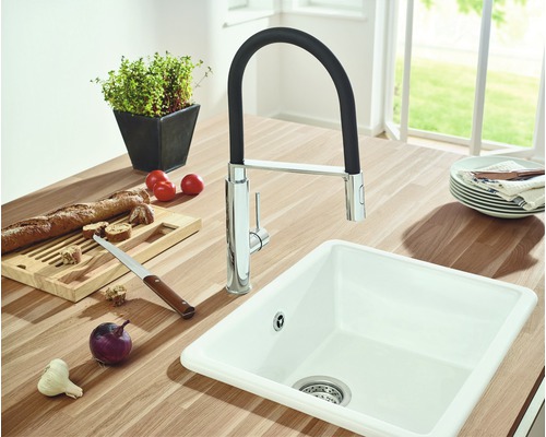 Küchenspüle mit Wasserhahn, umgeben von Lebensmitteln auf einer Arbeitsplatte.