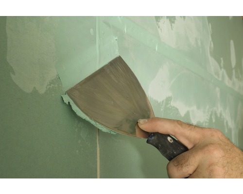Handwerker verspachtelt eine Trockenbauwand mit einem Spachtel