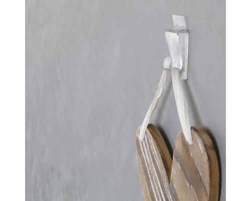 Dekoratives Holzherz hängt an einem transparenten Klebehaken an einer Wand.