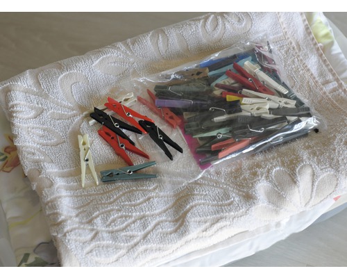 Verschiedene Wäscheklammern, einige in einer Plastiktüte, auf einem Handtuch