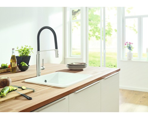 Küchenspüle mit Armatur auf einer Arbeitsplatte mit Lebensmitteln in einer hellen Küche.