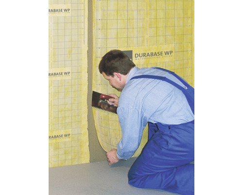Handwerker trägt Abdichtungssystem Durabase WP mit einer Glättekelle auf die Wand auf